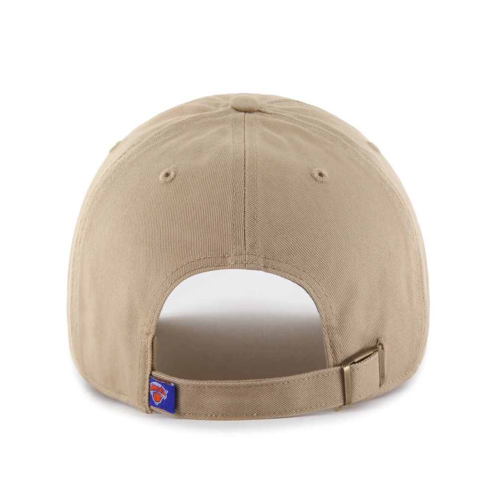 The New York Knicks '47 Clean Up Cap is a tan adjustable strapback baseball cap with a metal buckle and a small patch featuring the red and blue Knicks logo—ideal for fans who prefer a subtle team style.
