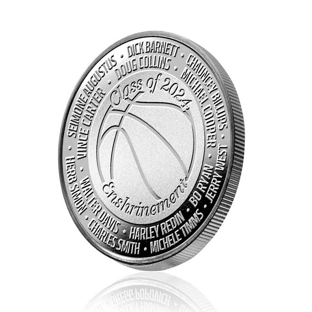 The Basketball Hall of Fame Enshrinement 2024 Coin is a limited edition collectible featuring a silver basketball, Class of 2024 Enshrinement, and engraved names of 2024 inductees, displayed upright on a white background.