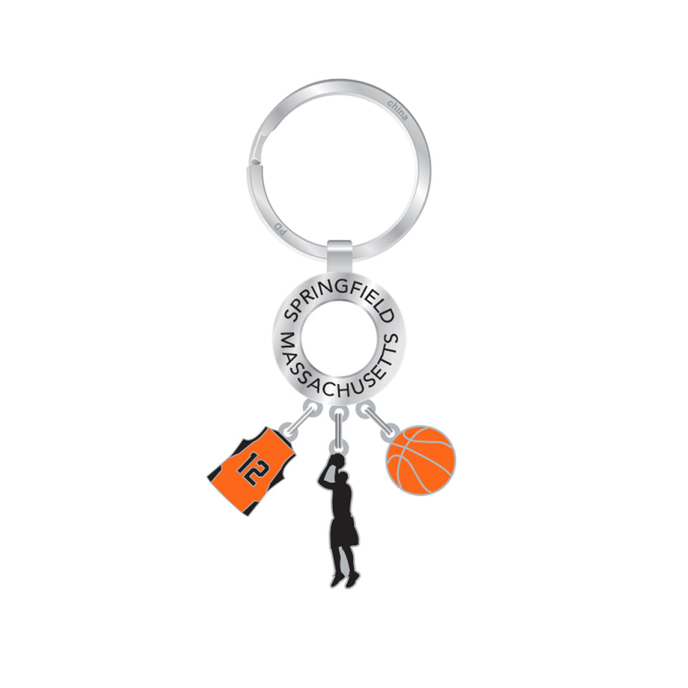 The Basketball Hall of Fame Dangle Keychain features three charms—an orange #12 jersey, a shooting player, and a basketball—with a ring inscribed SPRINGFIELD MASSACHUSETTS, making it the ideal unique basketball accessory.