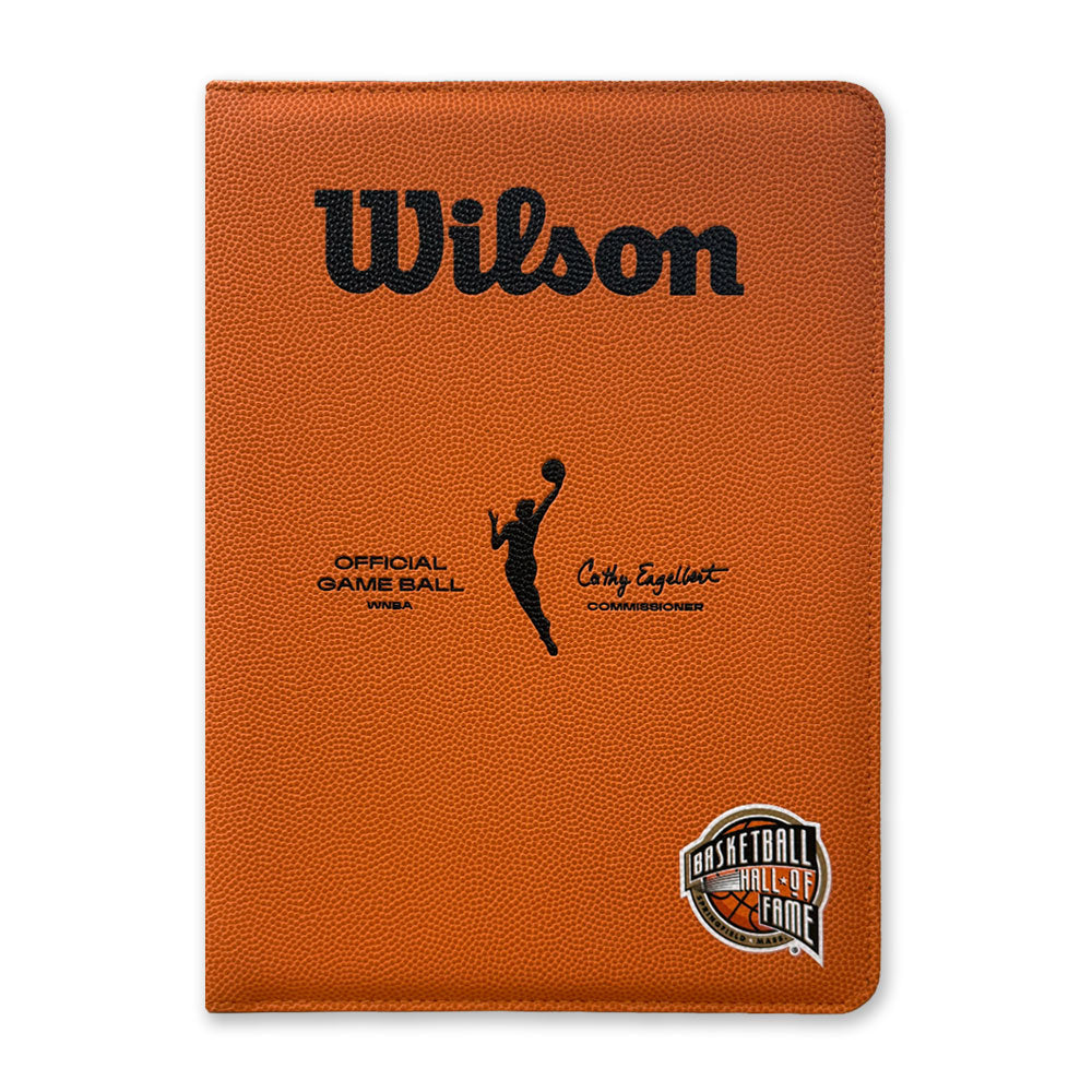 The Basketball Hall of Fame x Wilson WNBA Padfolio is a brown portfolio styled like a basketball, with the Wilson logo, a player silhouette, signature, and Basketball Hall of Fame logo on the bottom right corner.