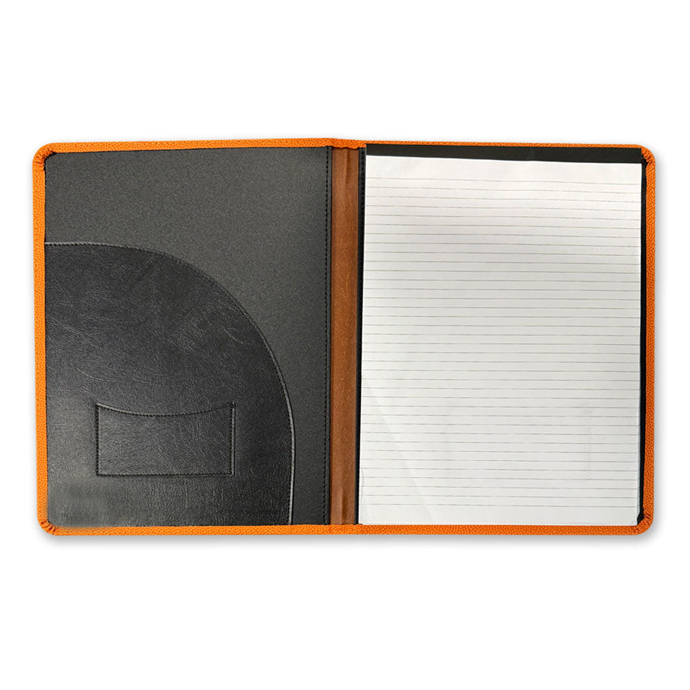 The Basketball Hall of Fame x Wilson WNBA Padfolio features orange edges, a lined notepad on the right, and a black folder with a small pocket on the left, all displayed open against a white background.