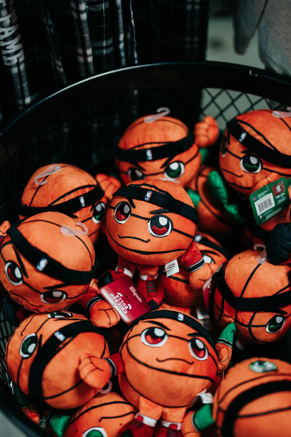 A basket filled with Boston Celtics Basketball Plush toys designed in Chibi art style, featuring basketballs with faces, headbands, and jerseys. Each plush has a determined expression, attached tags, and makes the perfect keepsake for Celtics fans.