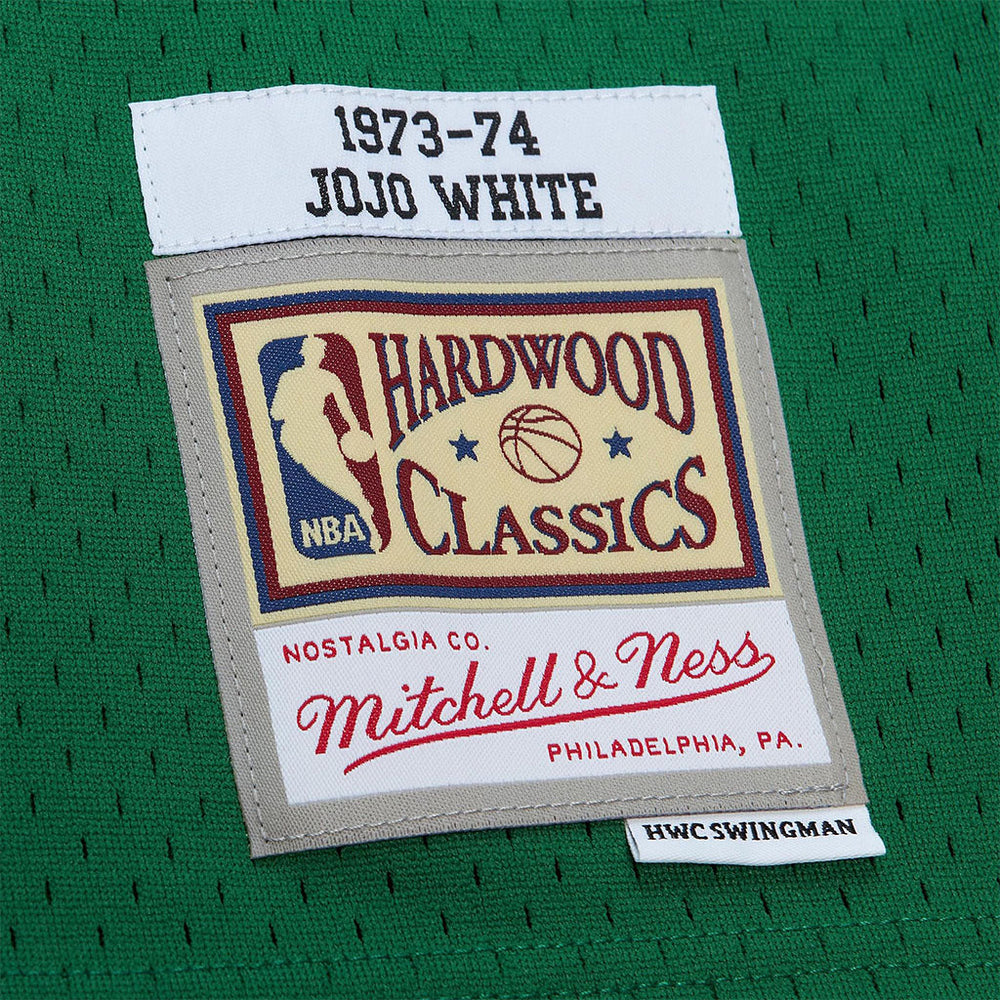 A close-up of the Swingman Jo Jo White Boston Celtics Dark 1973-74 Jersey, featuring green mesh fabric and sewn patches: one with "1973-74 Jo Jo White" and another Hardwood Classics NBA patch by Mitchell & Ness.